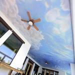 An outdoor porch ceiling of immense proportions and clouds of all types add air to this covered living space.